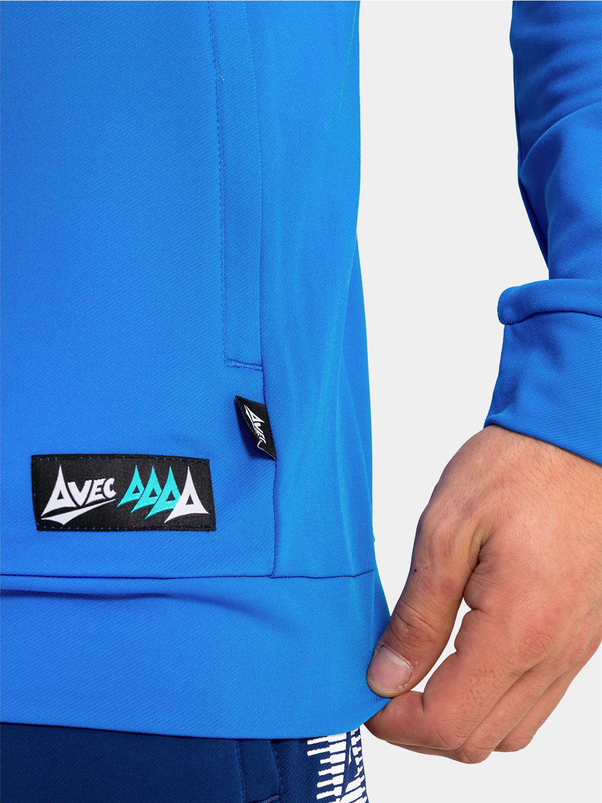 bottom-edge detail of the royal blue hoody, featuring the zip-pocket construction and official woven branding.