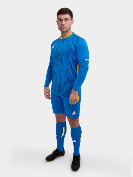 A model standing up wearing a royal blue and yellow football shirt, blue Shorts and blue Football Socks.