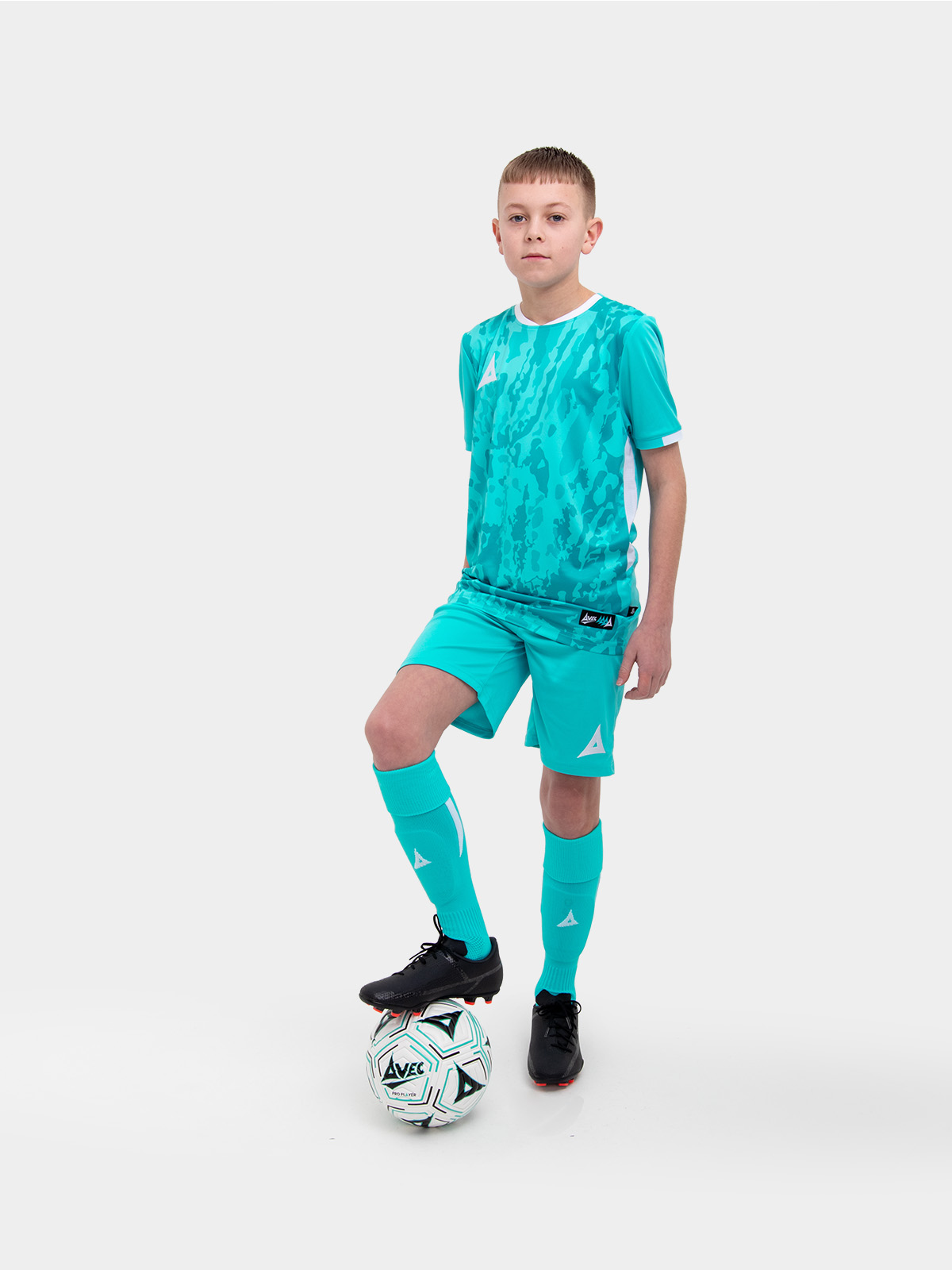 a kid standing up wearing a hyper blue football shirt, matching hyper blue shorts and hyper blue football socks.