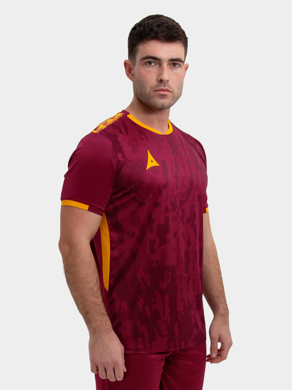 a model wearing a claret / maroon football shirt with amber accents