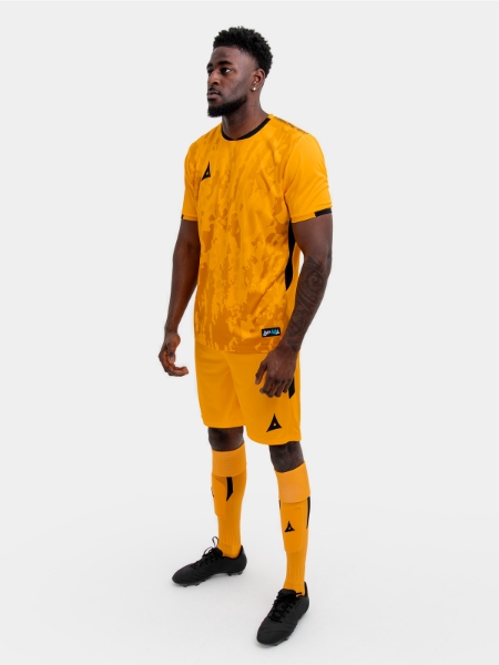 A model standing up wearing an amber and black football shirt, amber Shorts and amber Football Socks.