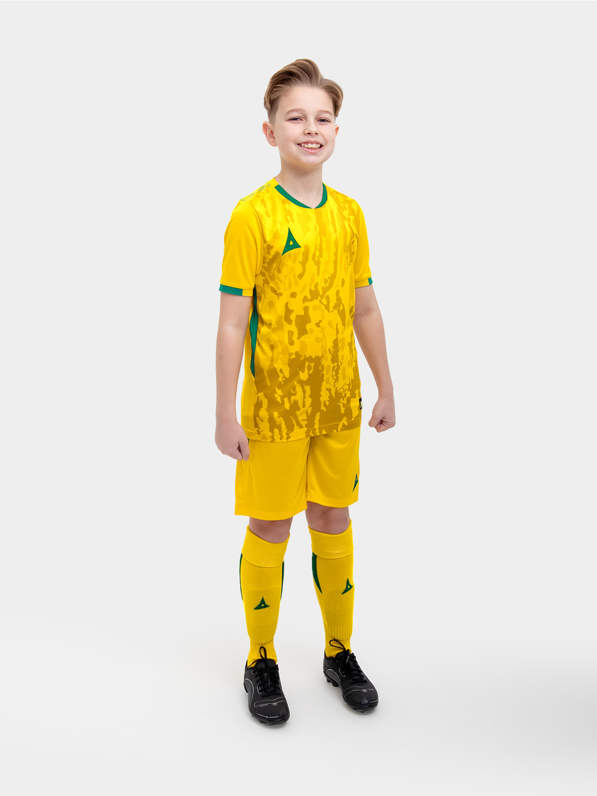 a kids football kit in yellow and matching red shorts and socks with green accent details