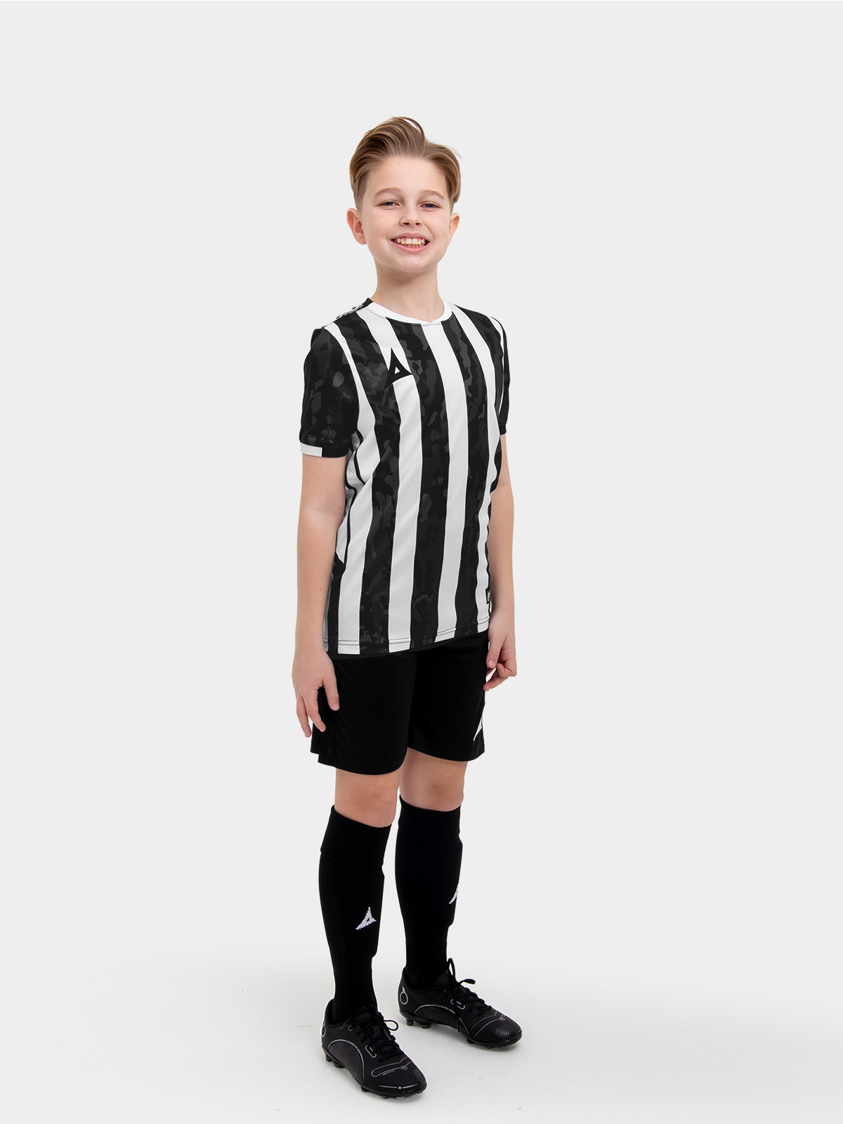 a young child in a black and white stripe shirt, black shorts and socks.