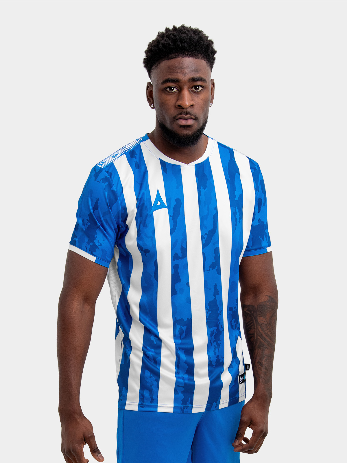 a man is wearing a royal blue and white stripe football shirt, which can be customised with a badge and sponsor for a grassroots team
