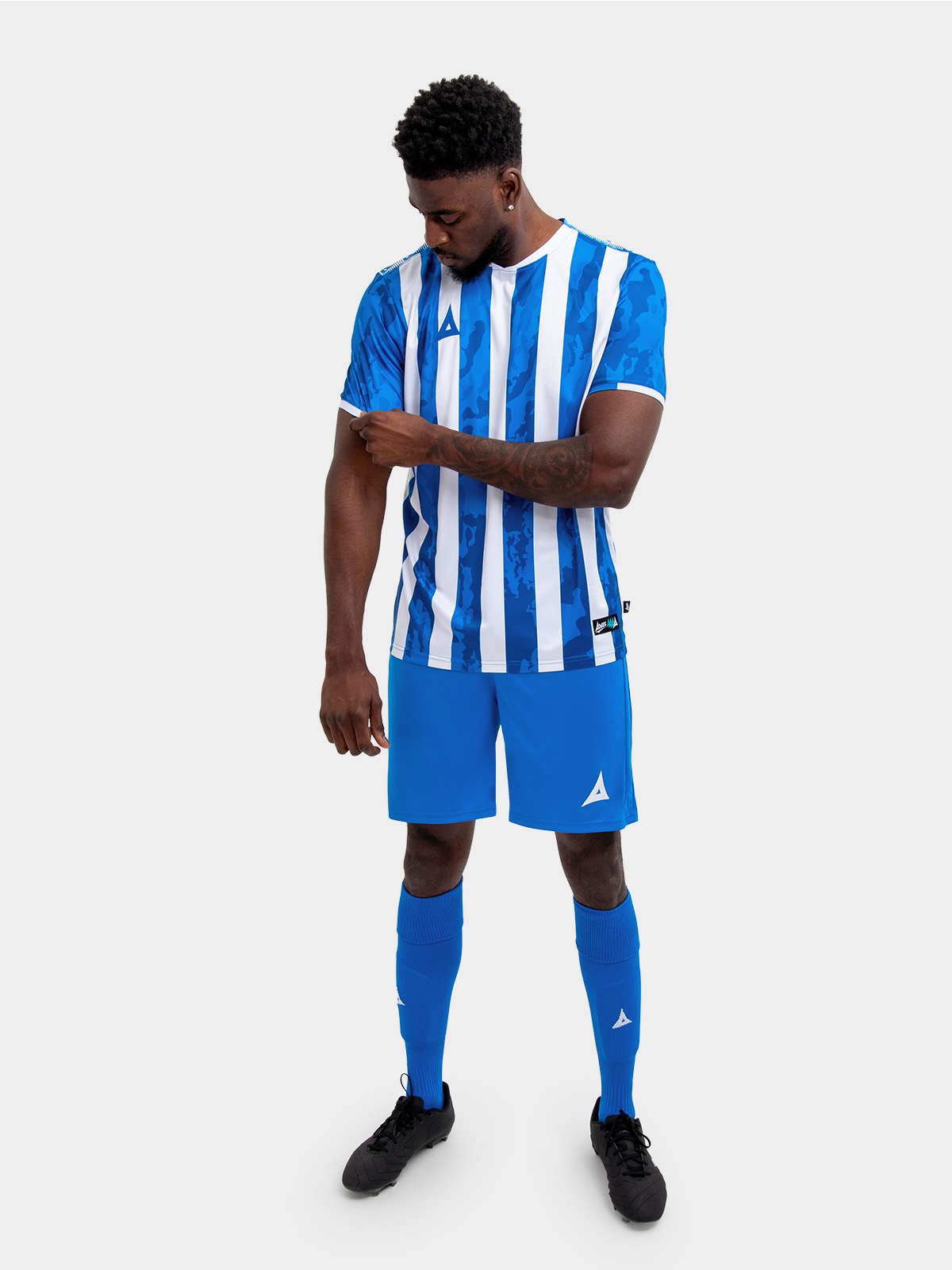 a man is wearing a royal blue and white stripe football shirt, with a royal blue pair of shorts and socks