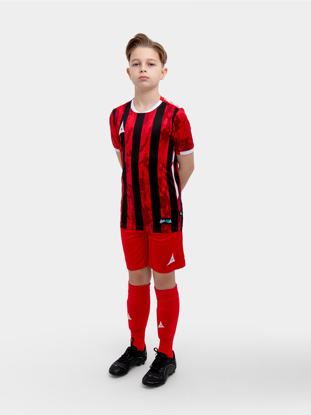 a kids football kit in red and black with stripes and matching red shorts and socks