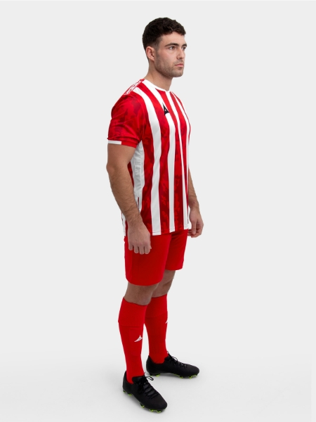 A model standing up wearing a red and white football shirt, red Shorts and red Football Socks.