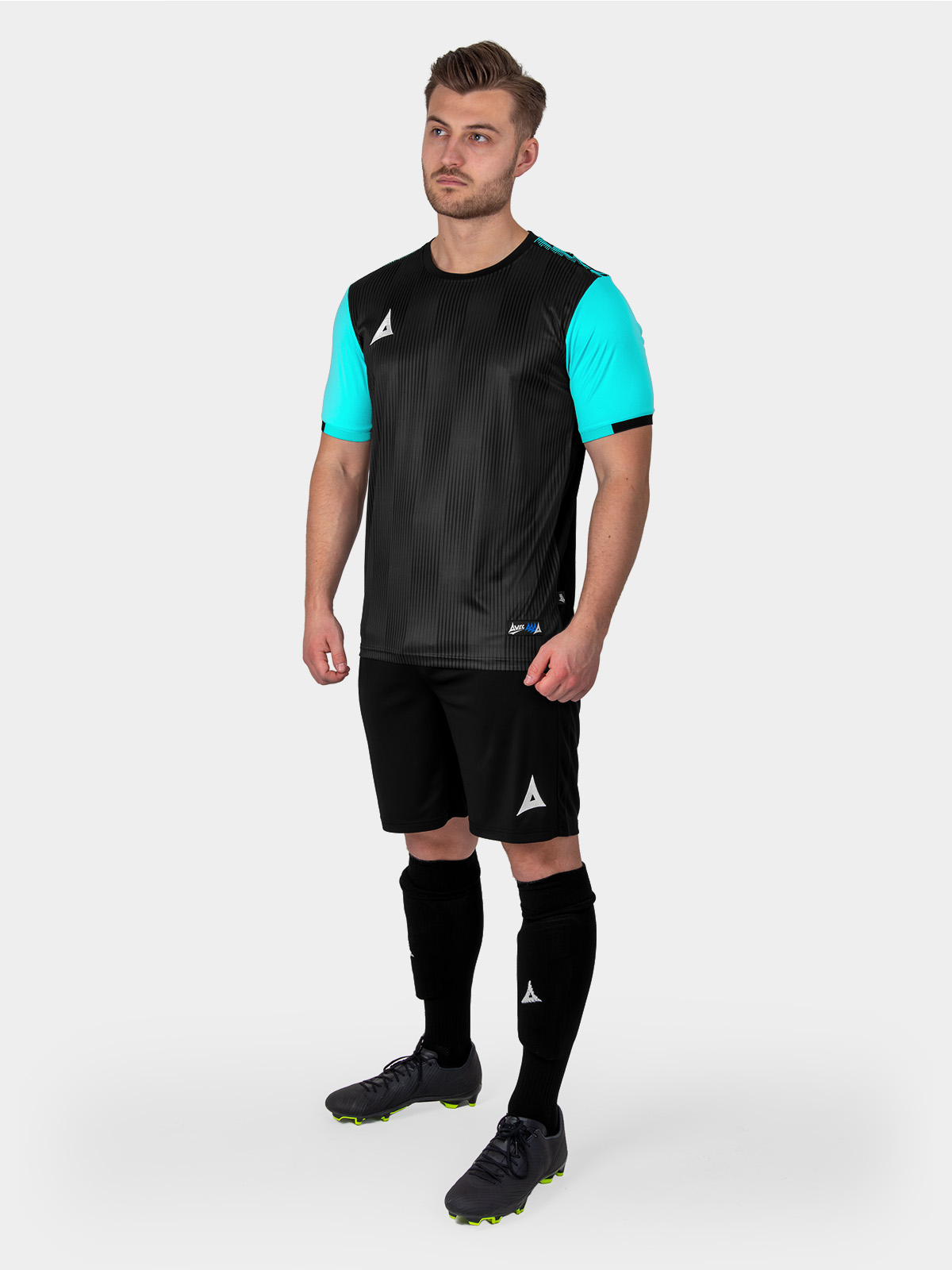 a man is wearing a black football shirt with pale blue sleeves, black shorts and light blue socks.
