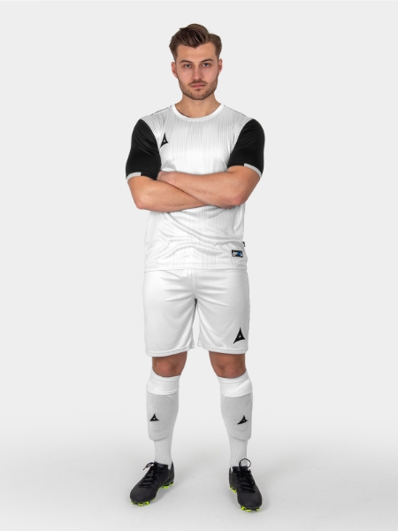 A football player is wearing a black and white football shirt, White shorts and white socks