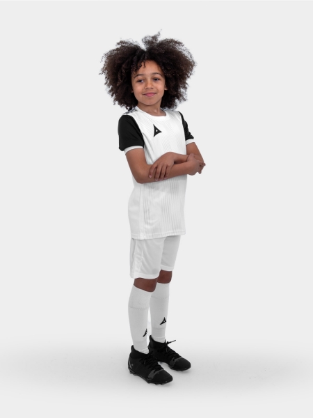 	A child is wearing a white football kit with black sleeves and trim. This combination is using white shirt, white shorts and white socks