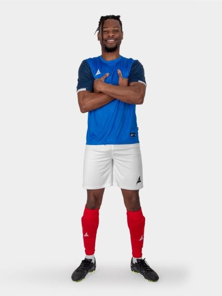 A man is wearing a royal blue and navy football shirt, combined with white shorts and red socks, akin to the France kit.