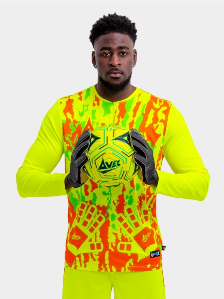 Man is wearing a neon yellow goalkeeper football shirt with orange accents and a neon yellow football