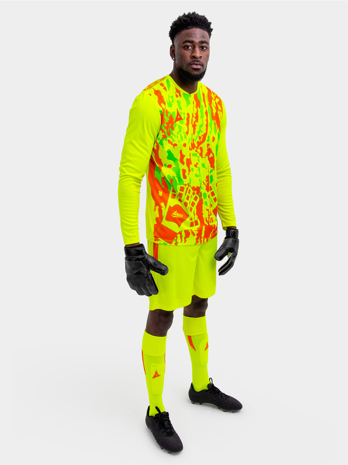 a model is wearing a full neon yellow goalkeeper football kit and holding a neon yellow football matching the kit