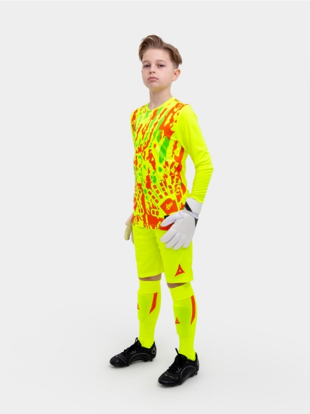	A young boy is wearing a full neon yellow goalkeeper football kit with an orange trim and detailing