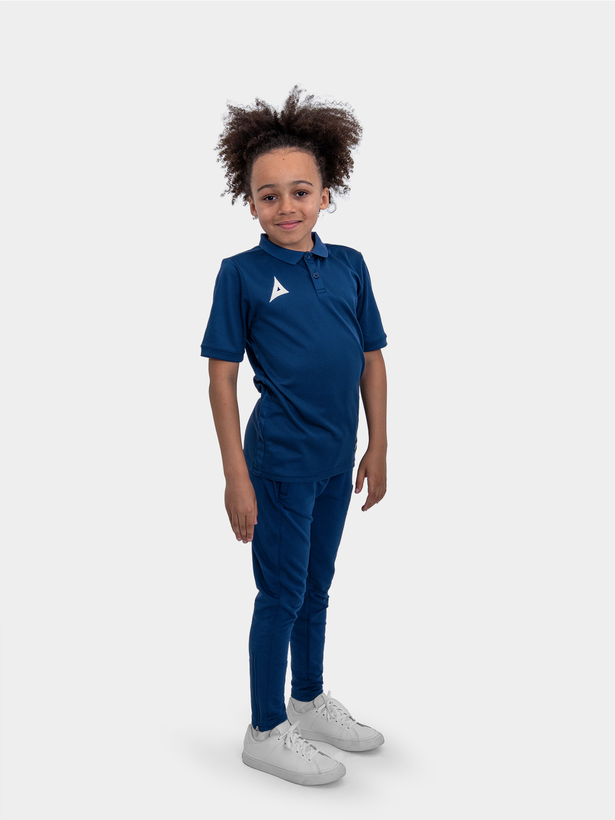 a boy is stood wearing the avec focus 2 navy tech polo and the avec focus 2 navy track pant for a smart combination