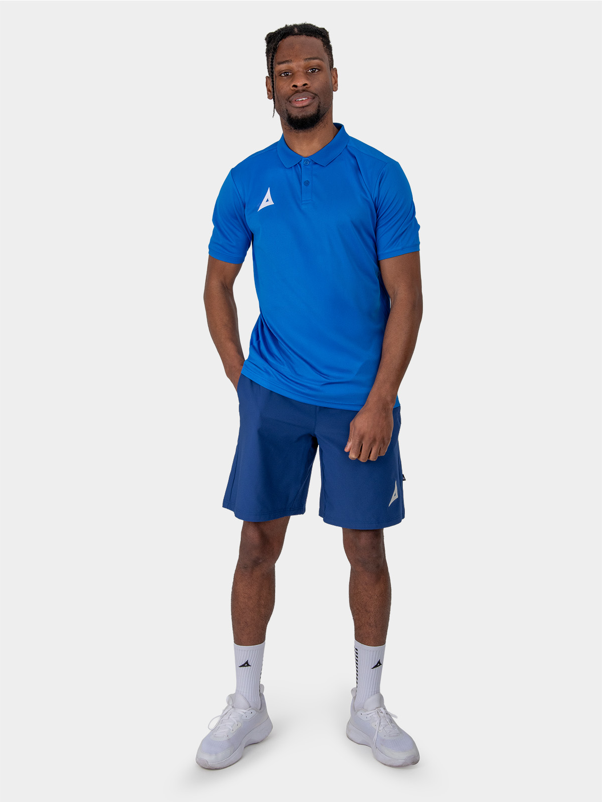 a male model is stood wearing the avec focus 2 royal tech polo, plain royal blue top and the avec focus 2 navy track pant