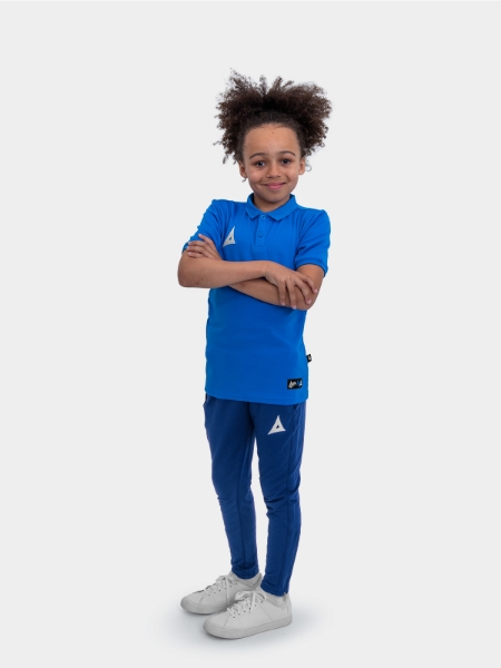 A boy is stood wearing the Avec Focus 2 Royal Tech Polo and the Avec Focus 2 Navy Track Pant