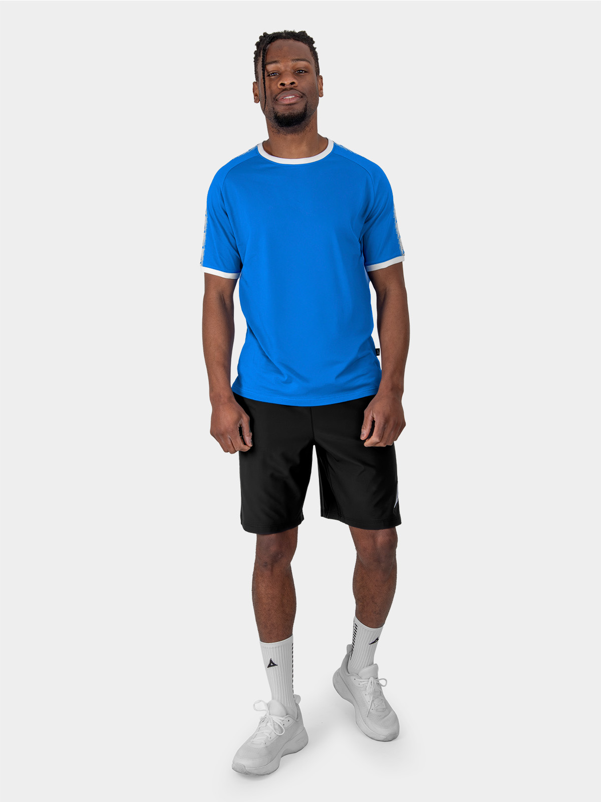 	a male model is stood wearing the avec evolve royal blue t-shirt, and black avec focus 2 tech shorts and avec grip socks in white