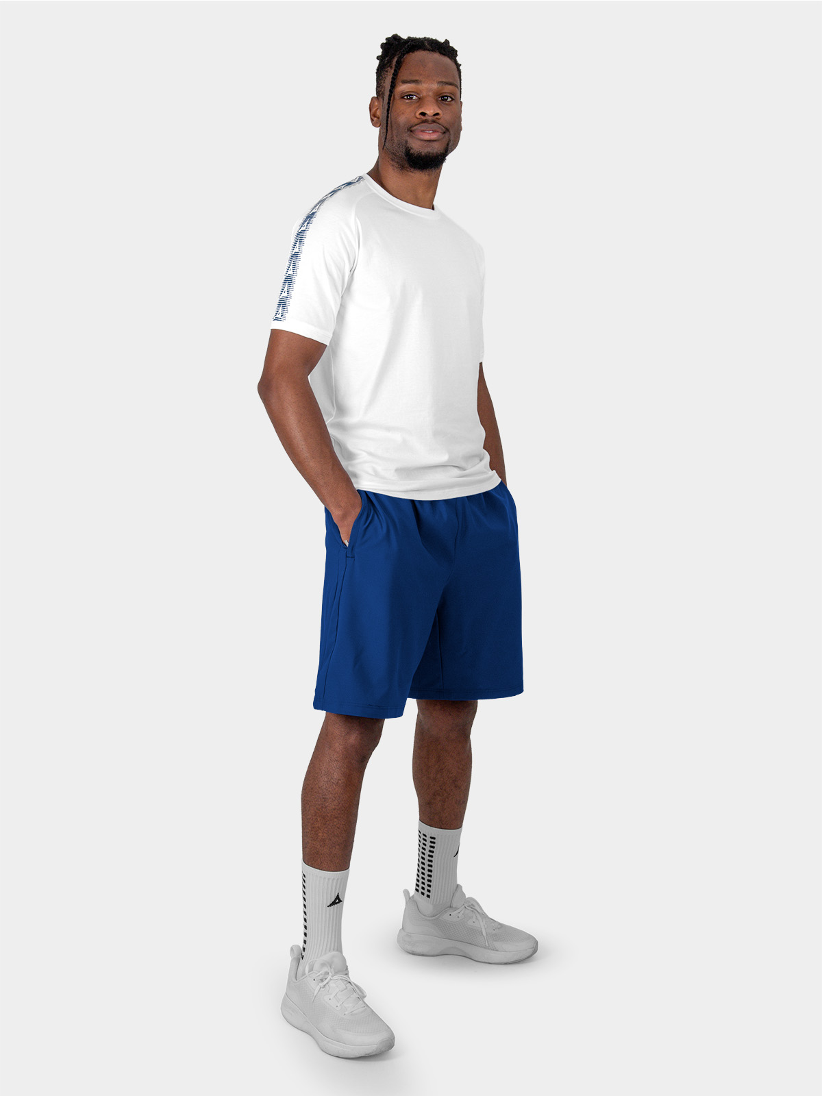 	a male model is sat wearing the cotton avec evolve white t-shirt, and navy avec focus 2 tech shorts and avec grip socks in white