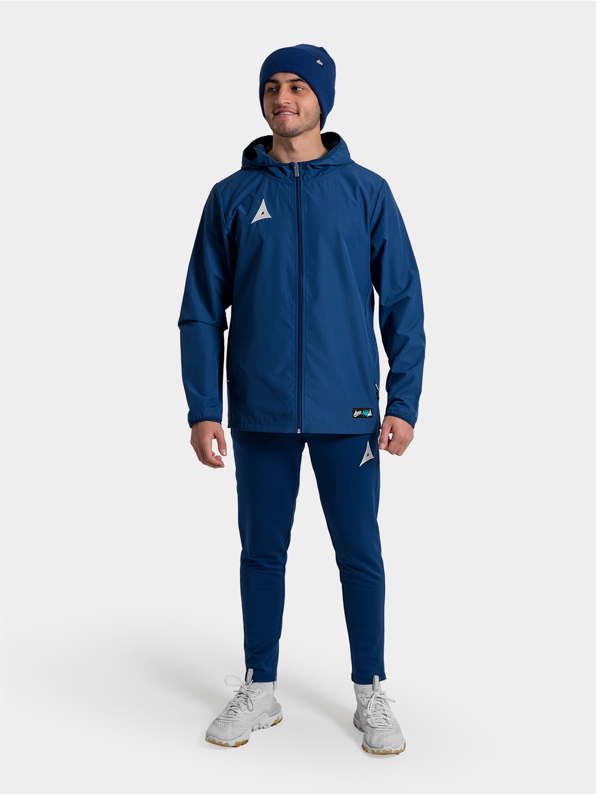 	a man wearing a navy rain jacket and a matching navy turn up beanie putting his hood up