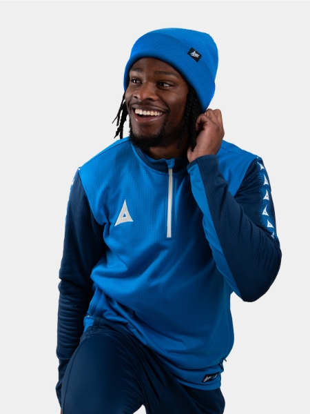 	A man keeping warm wearing a royal blue turn up bronx beanie