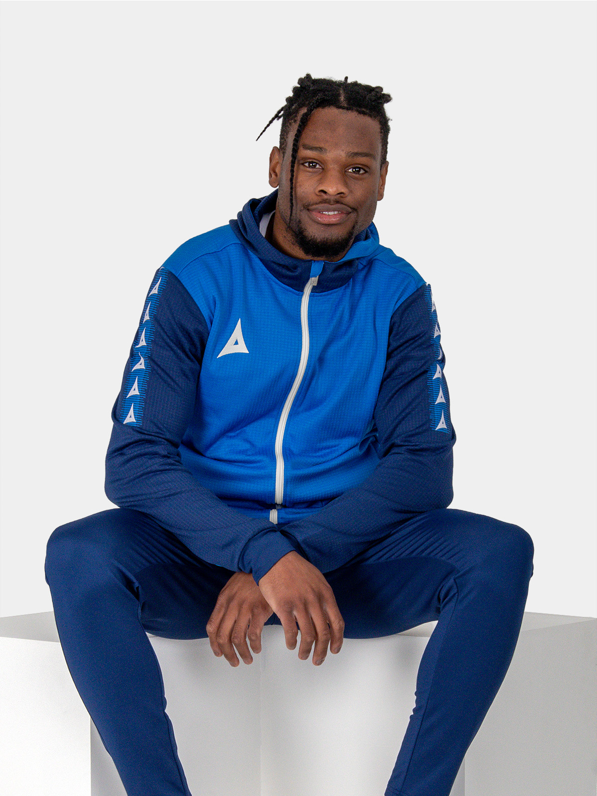 a man looking relaxed in a blue hoody featuring a white zip