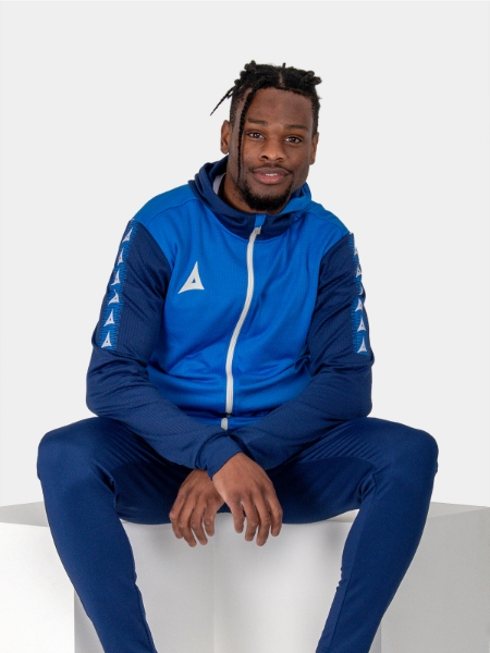 A man looking relaxed in a blue hoody featuring a white zip