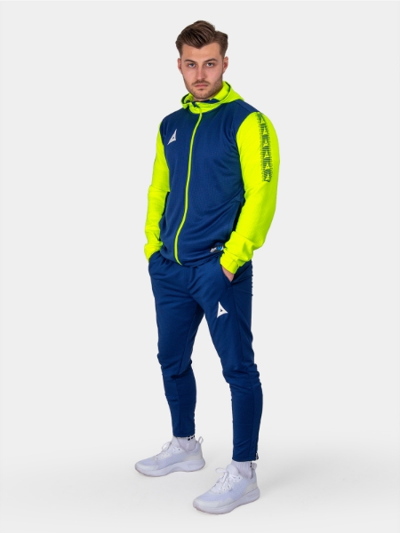 	A man sitting on a cube wearing a bright navy and yellow full zip hoody