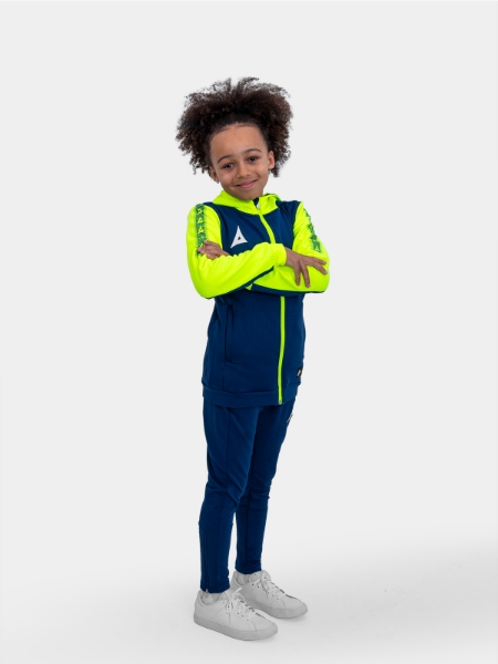 a young boy sitting on a box wearing a navy and yellow hoody and matching navy jogging bottoms