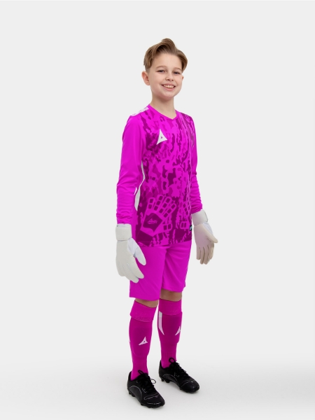	A kid standing up wearing a magenta goalkeeper football shirt, magenta Shorts and magenta Football Socks.