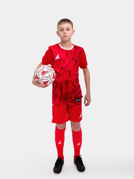 A young child is wearing a red Football Shirt. The football shirt has a camo pattern and matching red socks and shorts