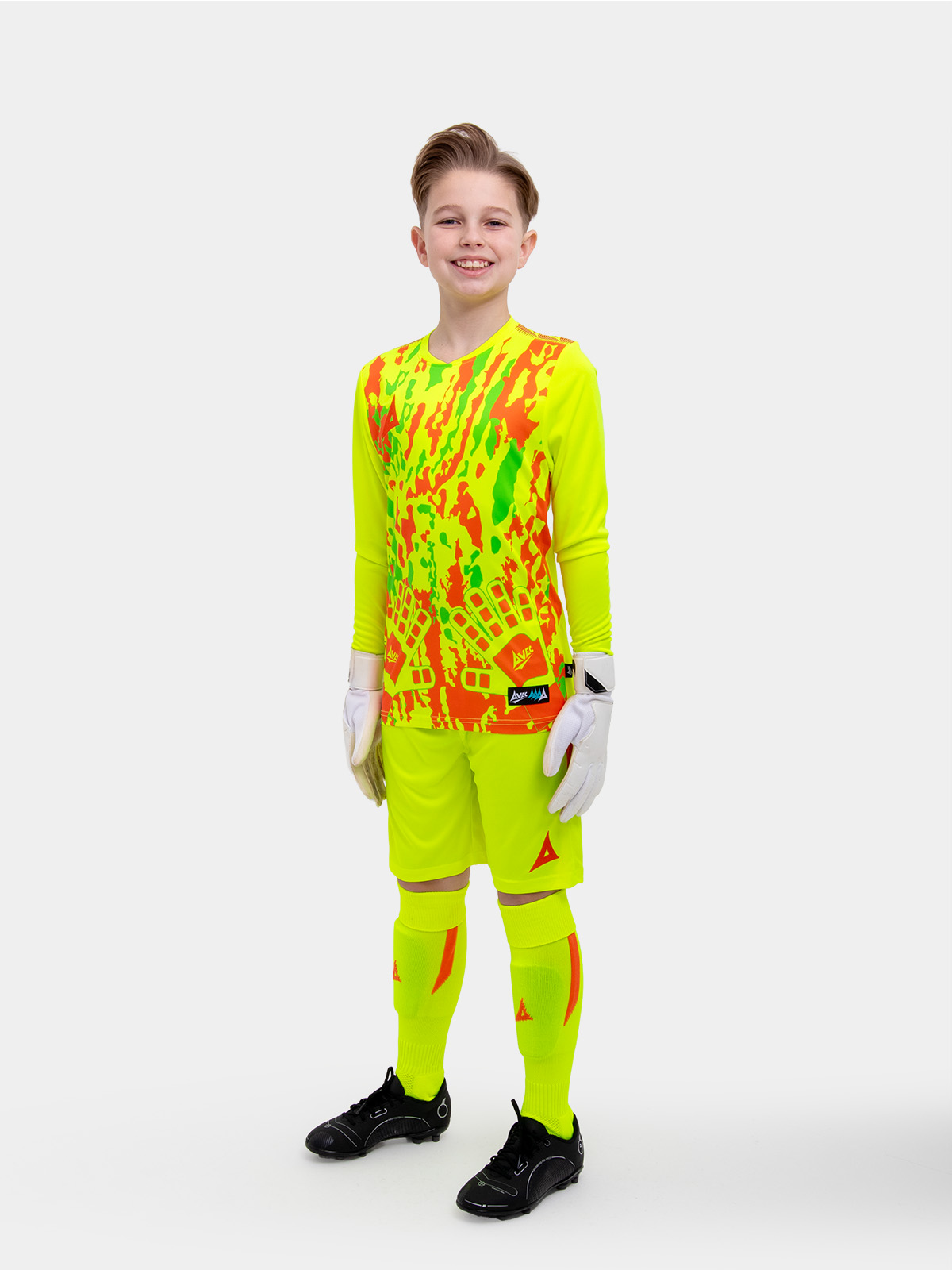 	a young boy is wearing a full neon yellow goalkeeper football kit with an orange trim and detailing