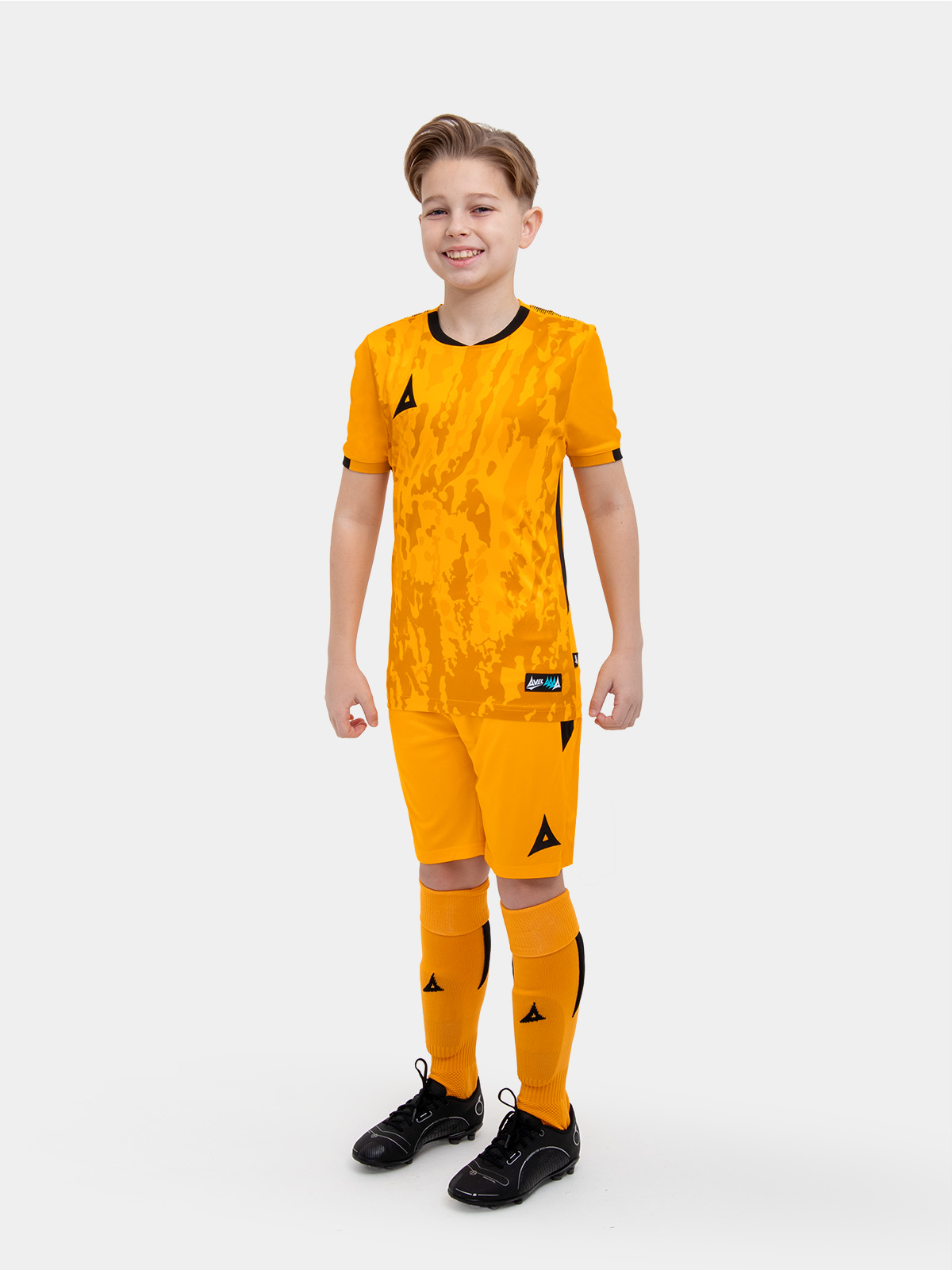 	a kids football kit in amber with black details and matching amber shorts and socks
