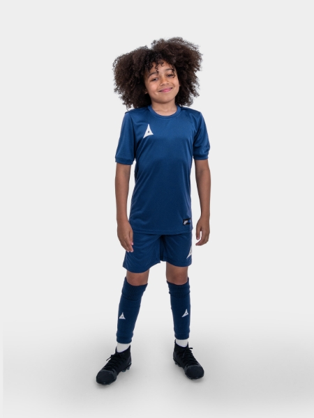 A boy is stood with his hands by his side with navy shorts on matching his t-shirt.