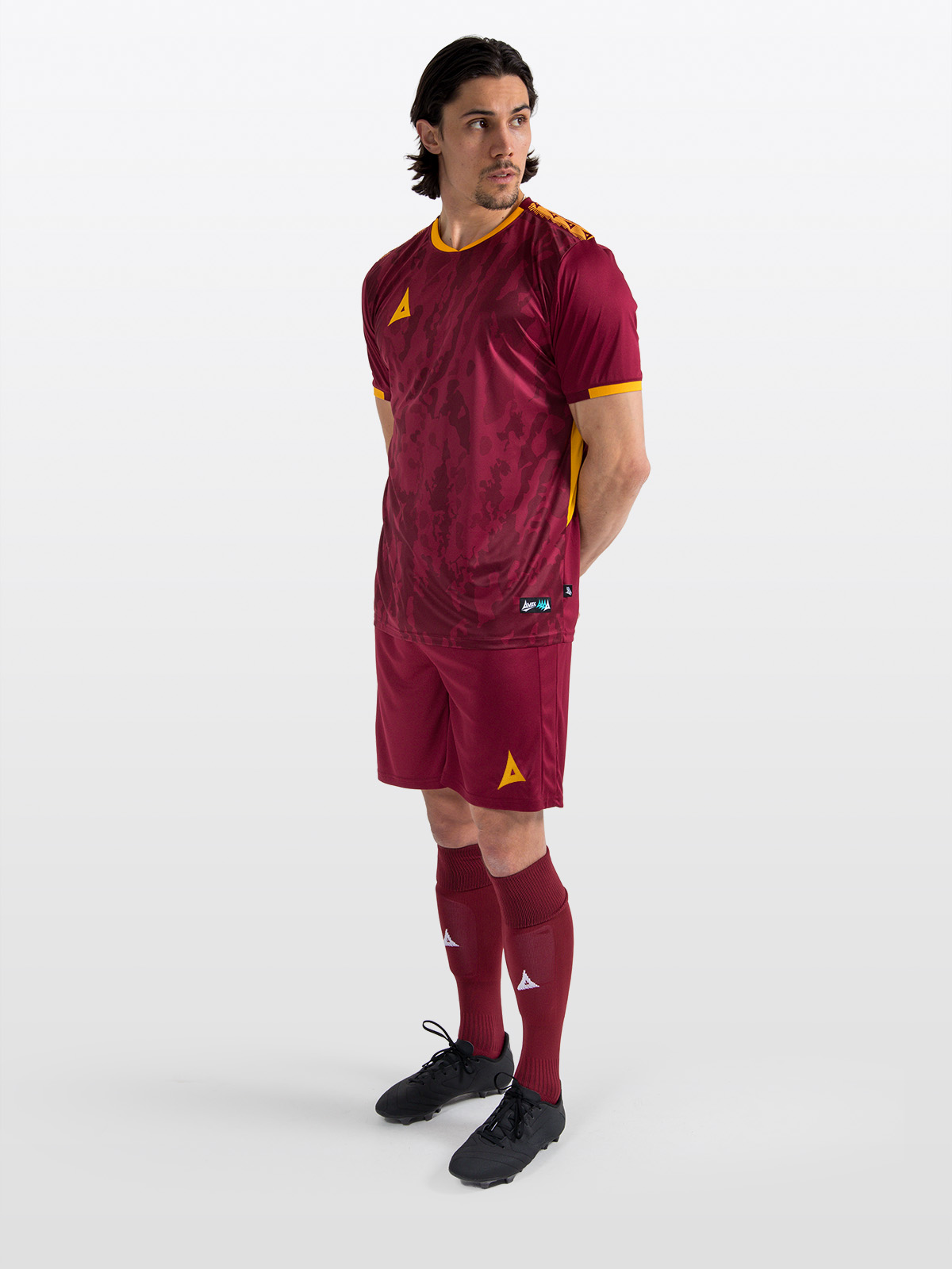 	a man in a football kit which is claret / maroon with matching claret shorts and socks