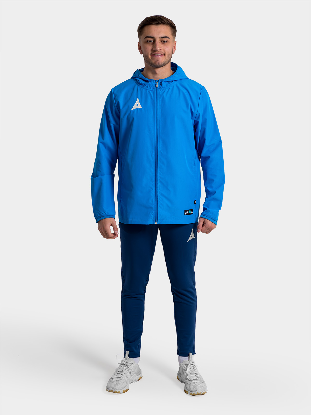 	full-body view of a player in the royal blue focus 2 shell jacket, ideal for pre-match warm-ups.