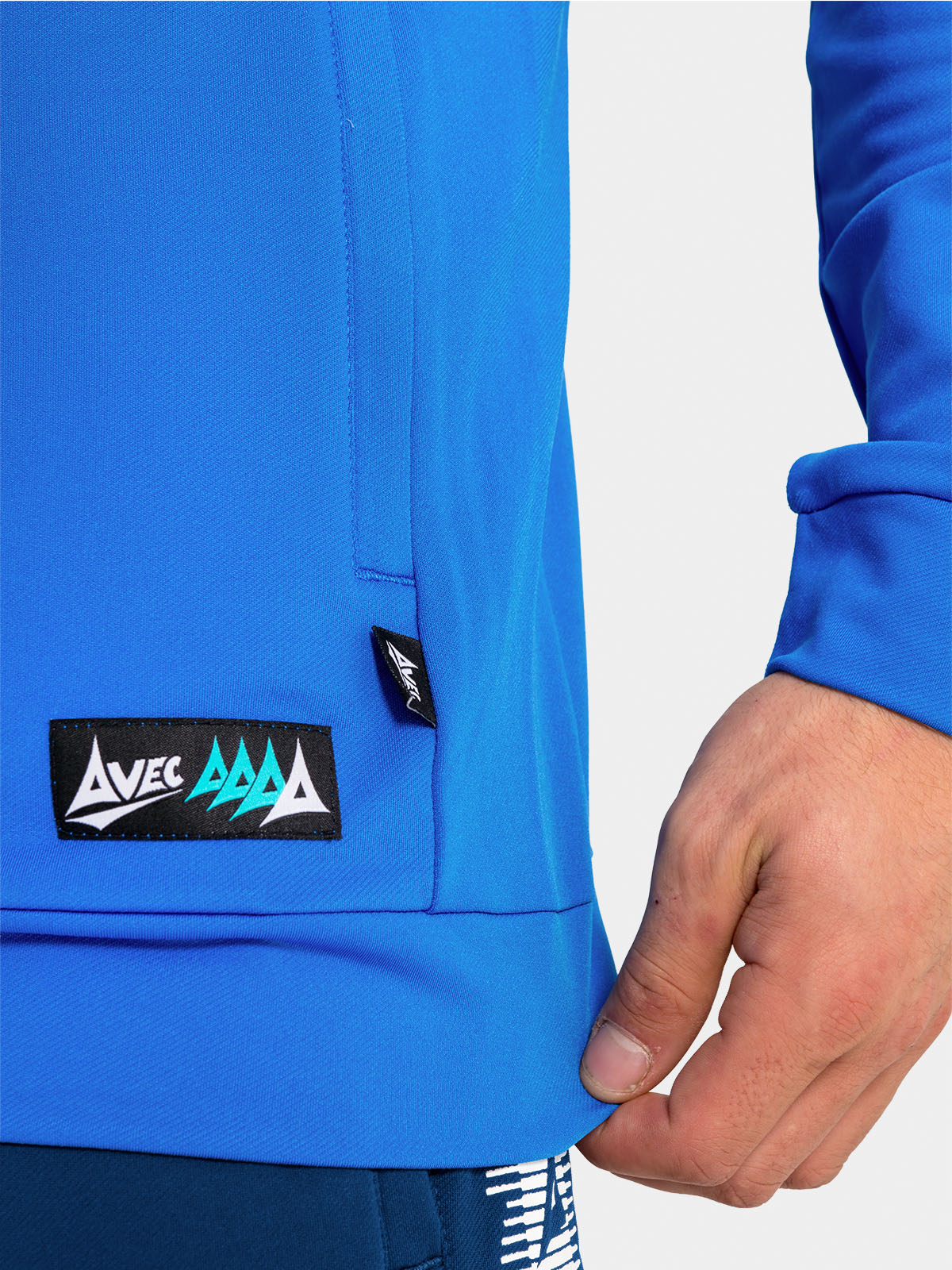 bottom-edge detail of the royal blue hoody, featuring the zip-pocket construction and official woven branding.