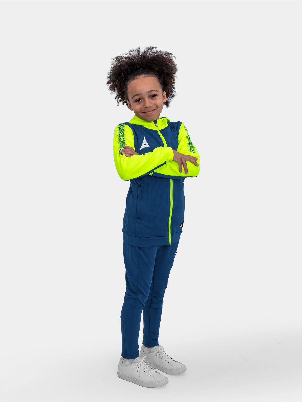 	a young boy sitting on a box wearing a navy and yellow hoody and matching navy jogging bottoms