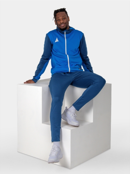 A man is stat down on a cube wearing a two-tone blue hoody