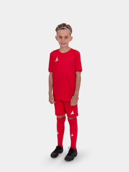 A young junior footballer wearing a matching red kit