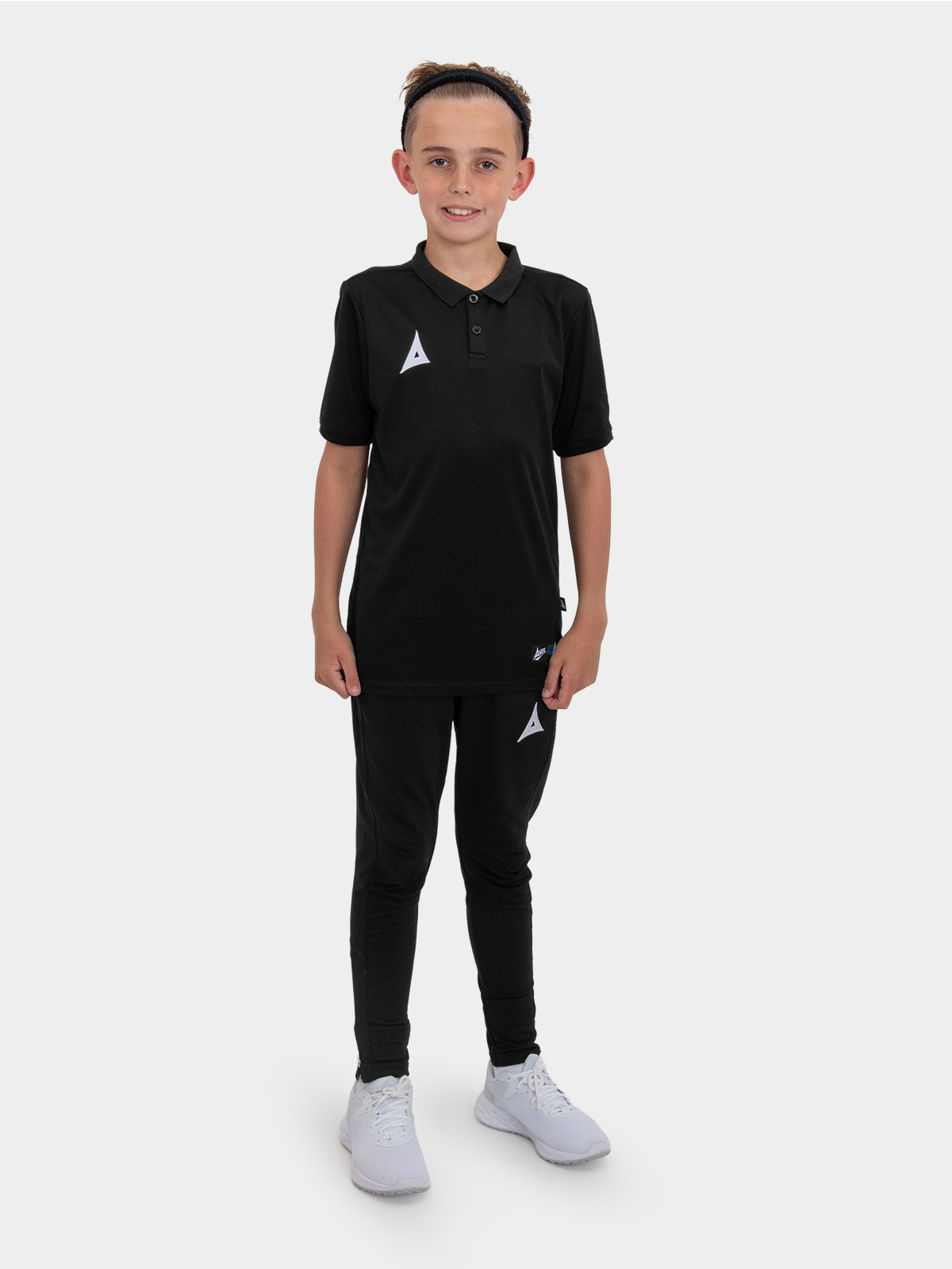	a boy is stood wearing the avec focus 2 black tech polo and the avec focus 2 black tech pant ready for training