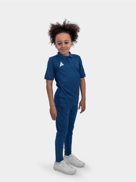 	A boy is stood wearing the Avec Focus 2 Navy Tech Polo and the Avec Focus 2 Navy Track Pant for a smart combination
