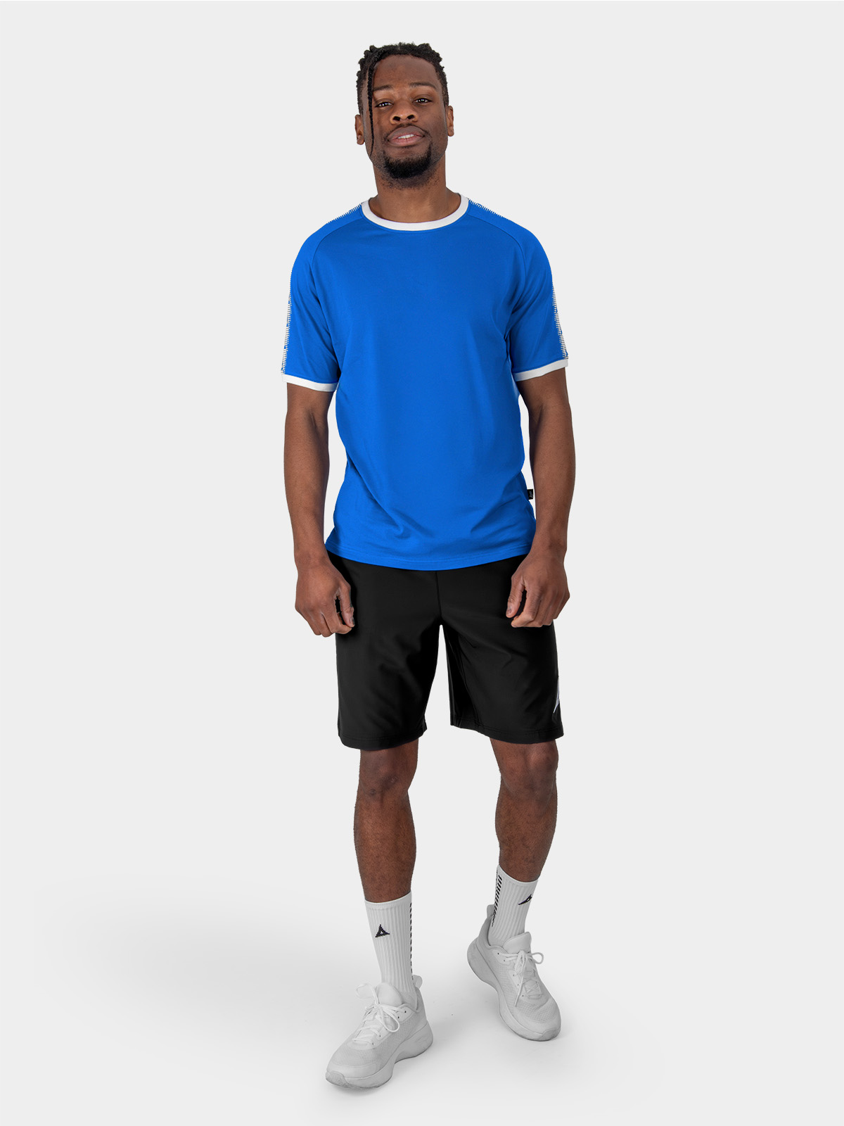 	a male model is stood wearing the avec evolve royal blue t-shirt, and black avec focus 2 tech shorts and avec grip socks in white