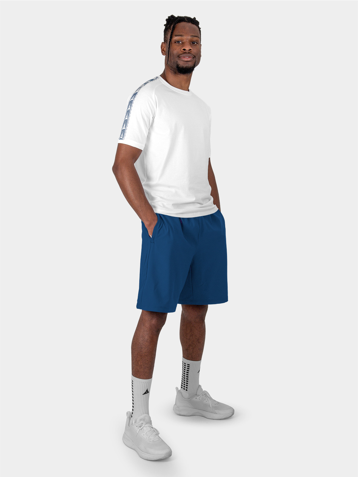 	a male model is sat wearing the cotton avec evolve white t-shirt, and navy avec focus 2 tech shorts and avec grip socks in white