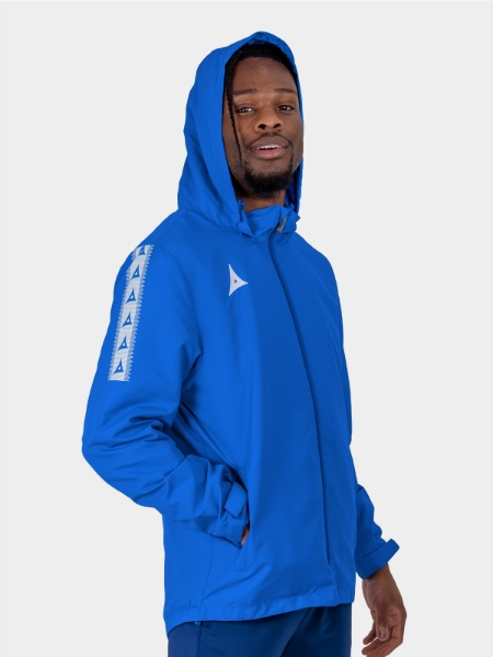 	Adult footballer deploying hidden hood on royal blue Evolve Rain Jacket in wet conditions