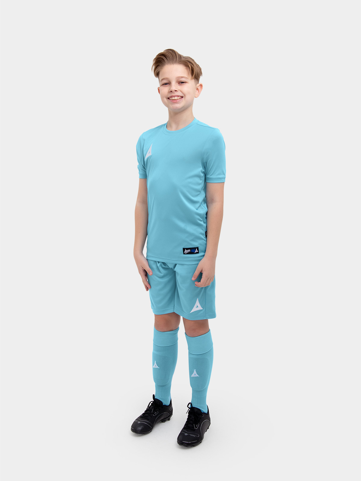 	a young child is wearing a sky blue football shirt. he has matching shorts and socks