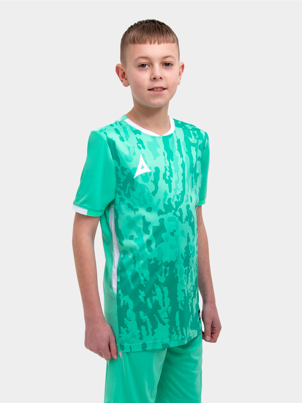 	a young child is wearing a mint green / hyper green football shirt . the football shirt has a camo graphic