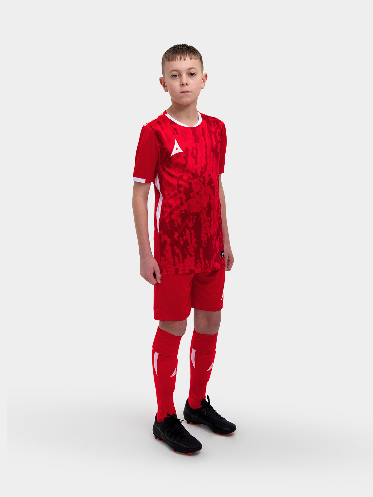 	a kids football kit in red with matching red shorts and socks