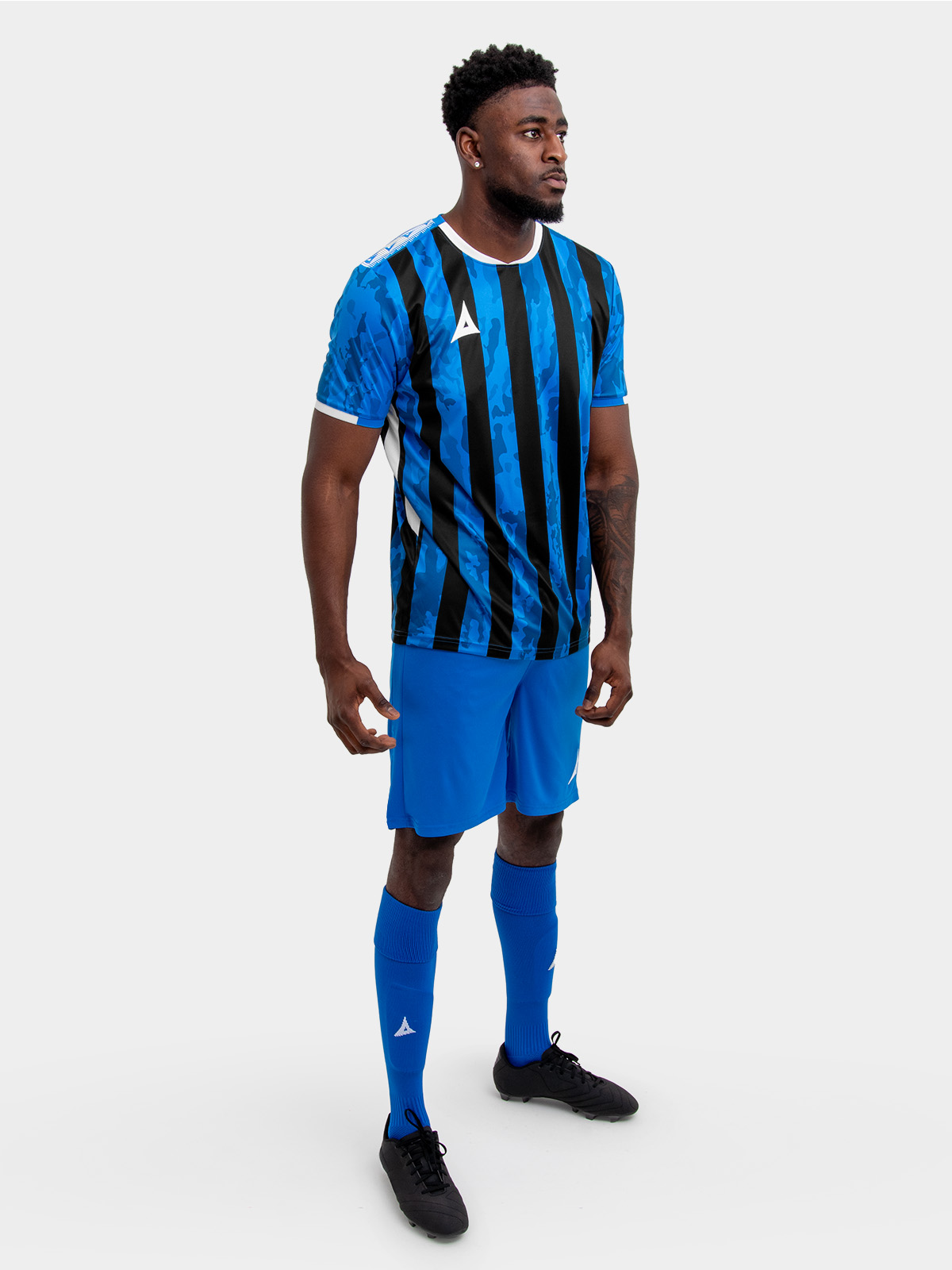 	a model standing up wearing a royal blue and black football shirt, royal blue shorts and royal bluefootball socks.