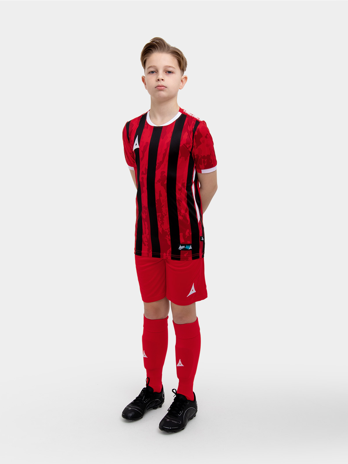  	a kids football kit in red and black with stripes and matching red shorts and socks